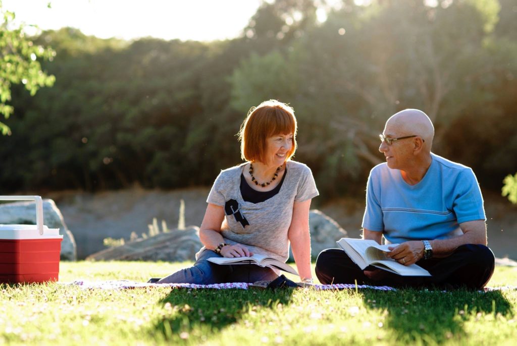 man and woman reading together on picnic blanket