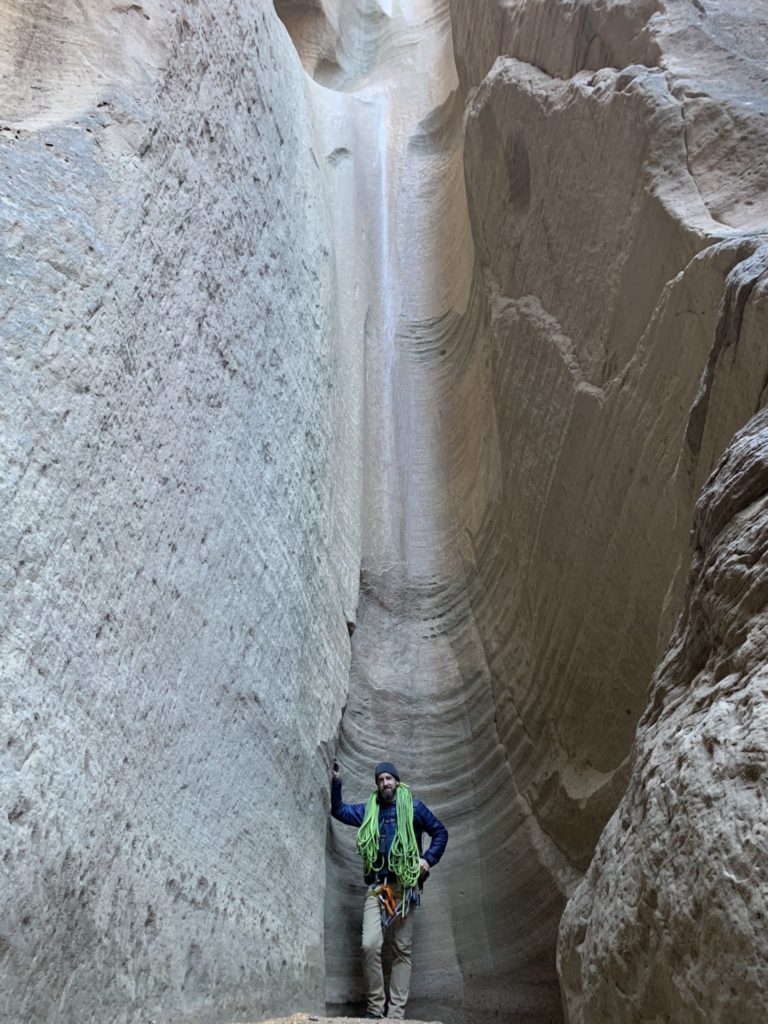 Man with rope standing at bottom of slope